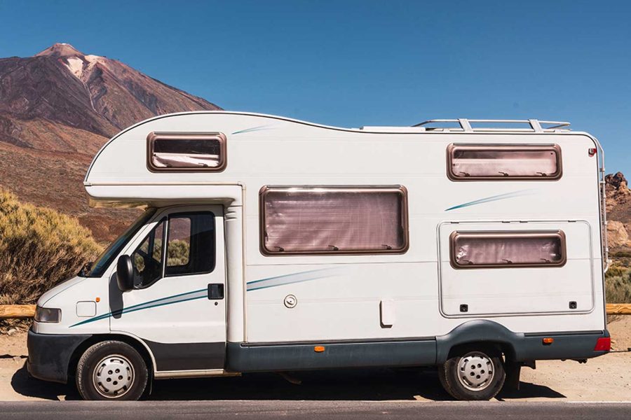 camper-van-on-road-near-hill-and-blue-sky-2021-12-09-12-34-12-utc.jpg